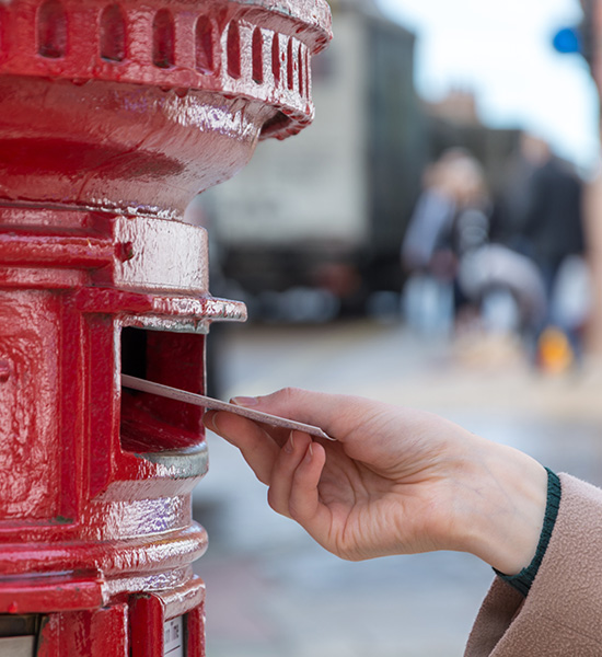 A customer posting a letter into a red post box